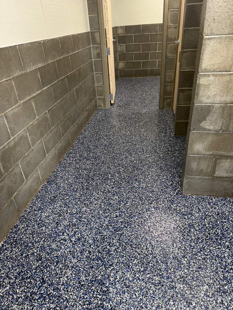 Blue and white flake epoxy floor in a commercial restroom hallway with block walls