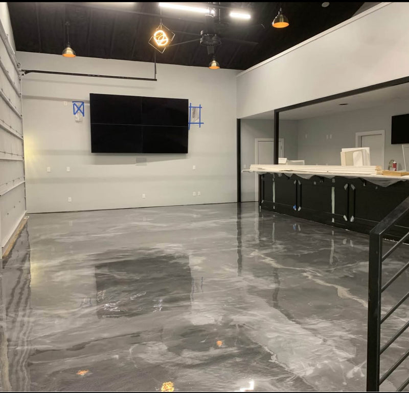Gray and white metallic epoxy floor in a room with a wall-mounted TV