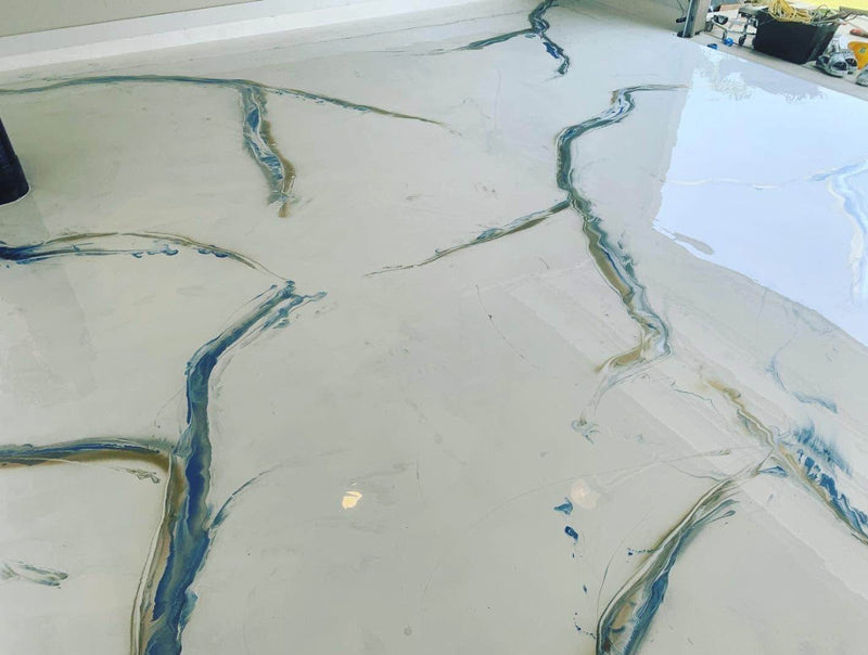 Cream metallic epoxy floor with fine blue and copper vein accents