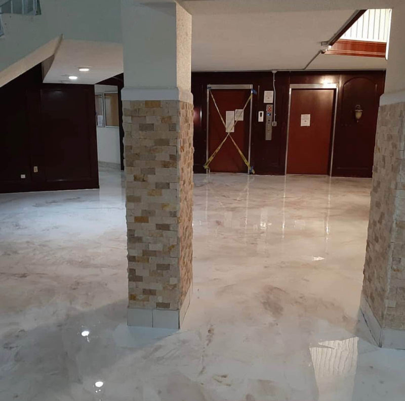 White and cream marble-look metallic epoxy floor in a commercial lobby with stone columns