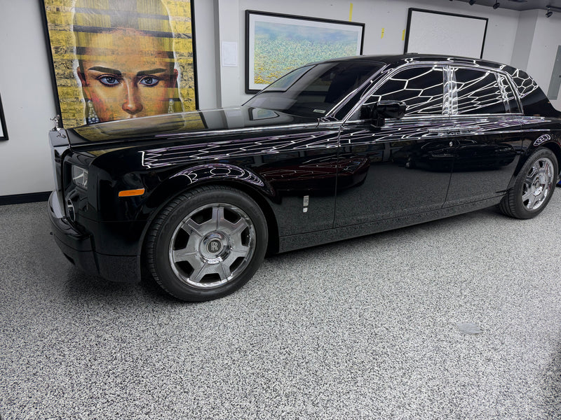 Gray flake epoxy showroom floor with a black Rolls-Royce Phantom