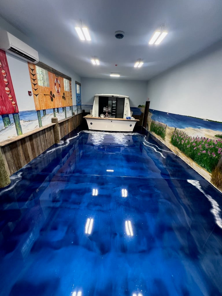 Deep blue ocean-themed epoxy floor with a nautical mural and boat