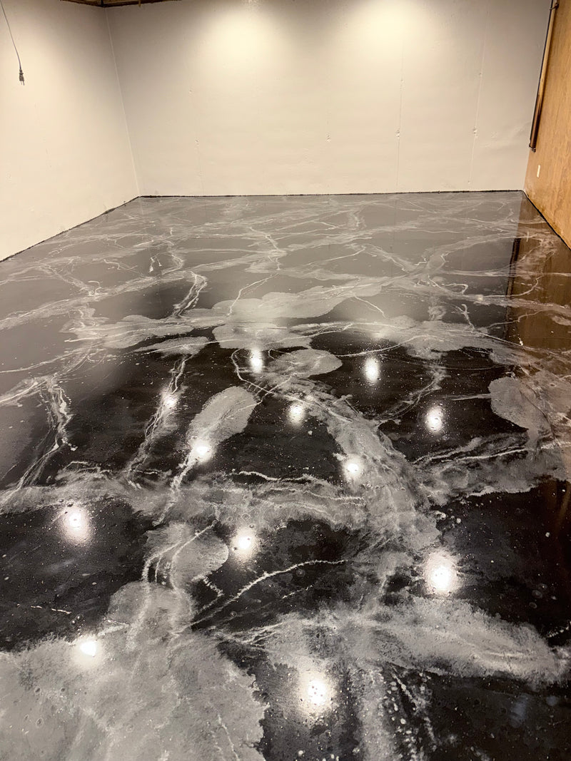 Black, silver and white marbled metallic epoxy floor in a dark room