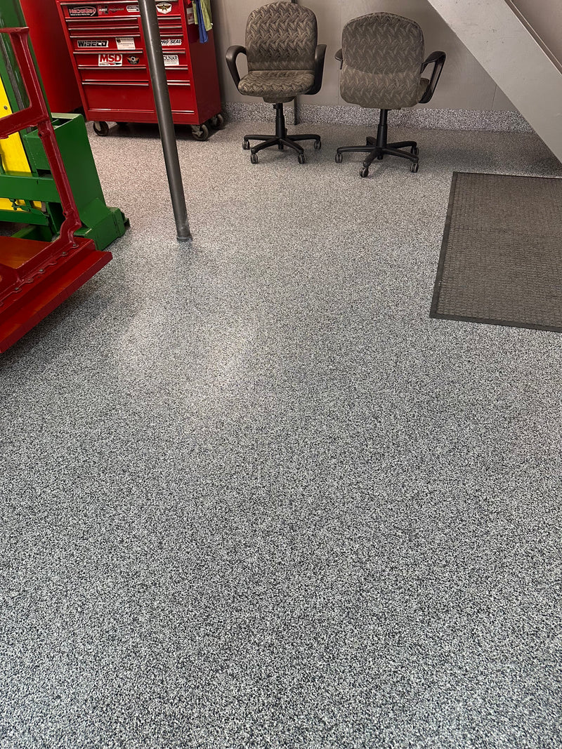 Gray, black and white flake epoxy floor in a workshop with tool chests and office chairs